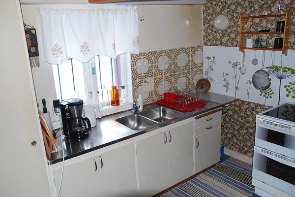 Huset har et ældre køkken med køleskab, komfur, ovn, mikroovn